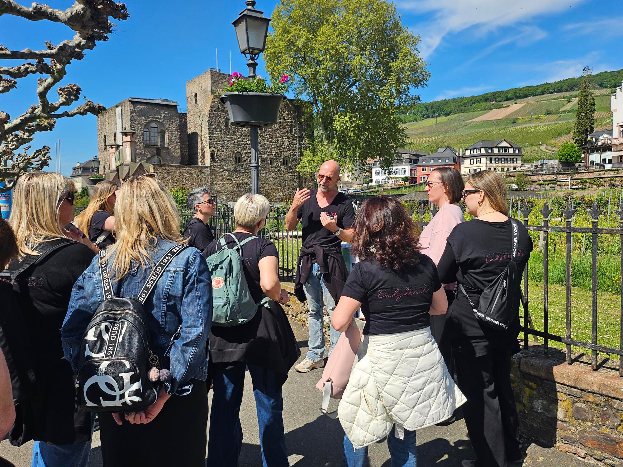 Gruppe lauscht dem Guide vor historischer Burg in Rüdesheim